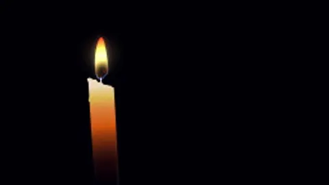 A single candle flame swaying in the dark.